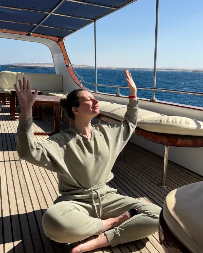 Élodie en méditation, bras levés vers le soleil, face à la mer
